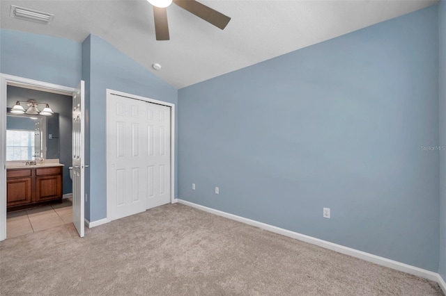 unfurnished bedroom featuring visible vents, baseboards, lofted ceiling, a closet, and light colored carpet