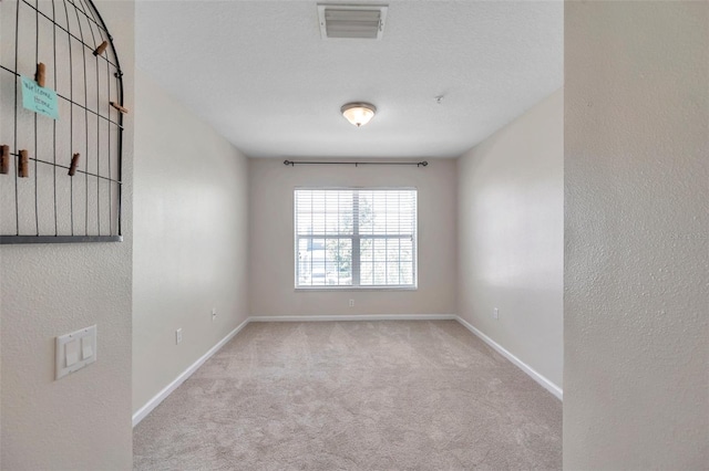 carpeted spare room with visible vents and baseboards