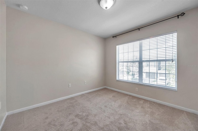 carpeted spare room featuring baseboards