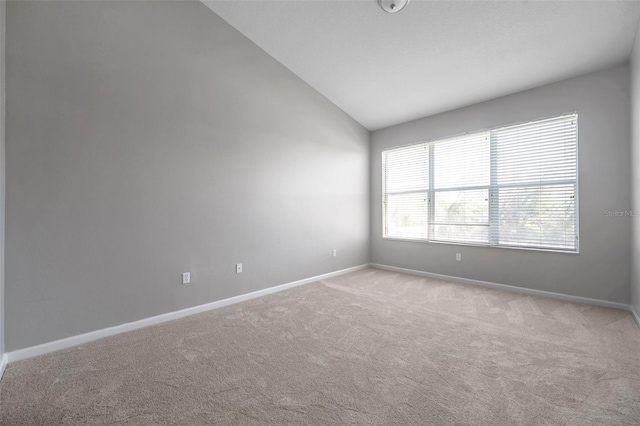 unfurnished room featuring baseboards, light carpet, and vaulted ceiling