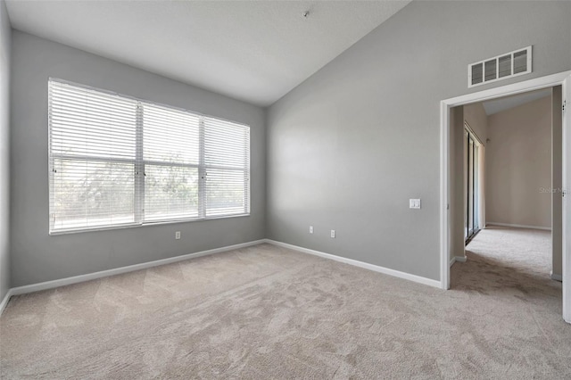 carpeted spare room with visible vents, high vaulted ceiling, and baseboards