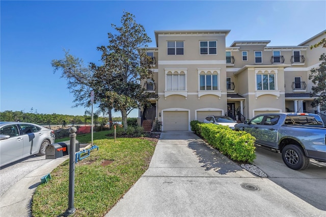 view of property with stucco siding, a front yard, concrete driveway, and an attached garage