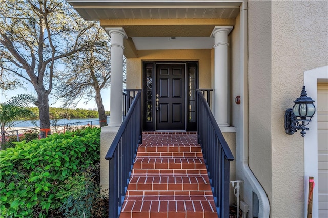 view of exterior entry with a water view and stucco siding