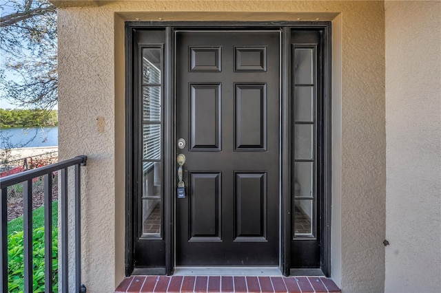 property entrance featuring stucco siding and a water view