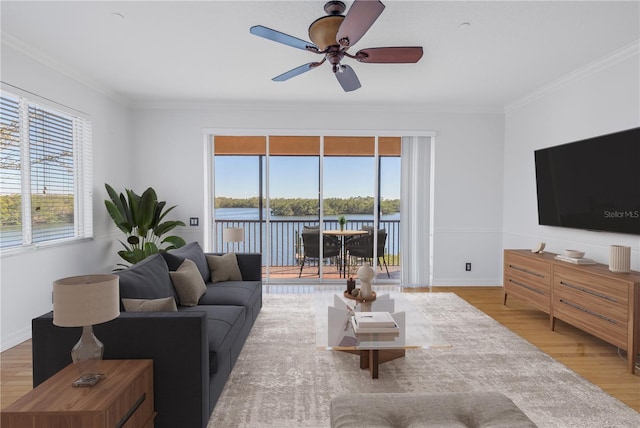 living room featuring light wood-style flooring, a ceiling fan, baseboards, and ornamental molding