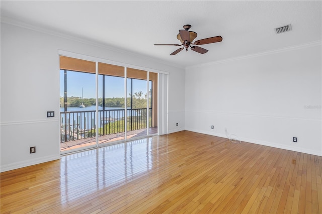 spare room featuring crown molding, visible vents, light wood finished floors, and ceiling fan