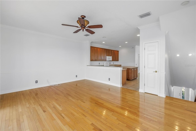 unfurnished living room featuring visible vents, ornamental molding, a ceiling fan, light wood finished floors, and baseboards