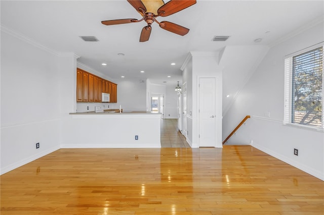 unfurnished living room featuring ceiling fan, crown molding, visible vents, and light wood-type flooring