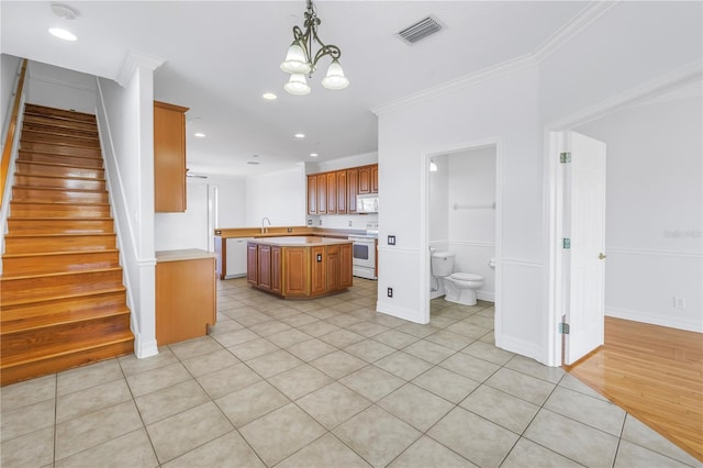 kitchen featuring white appliances, visible vents, a sink, light countertops, and crown molding