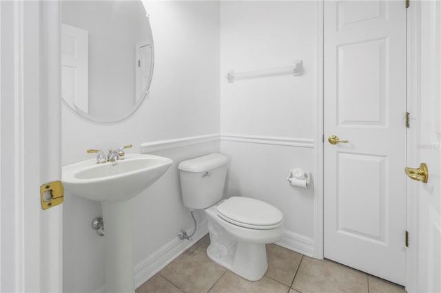 half bath with tile patterned floors, toilet, and baseboards