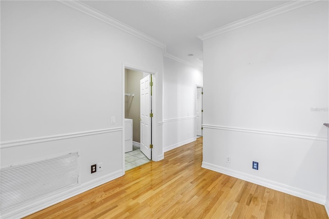 empty room with crown molding, wood finished floors, baseboards, and visible vents