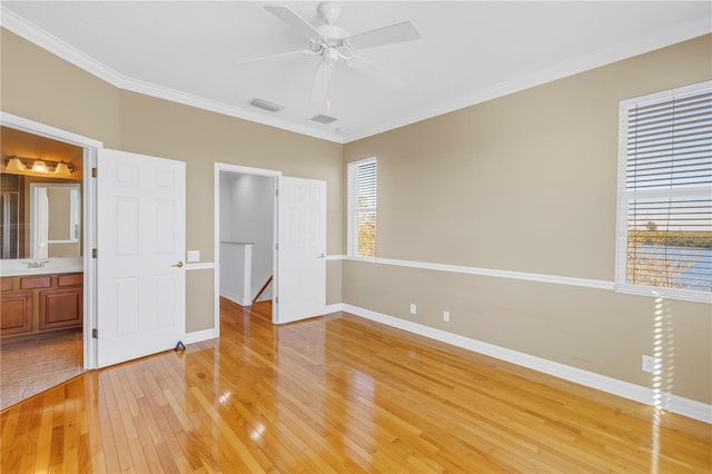 unfurnished bedroom with visible vents, baseboards, light wood-style floors, and crown molding