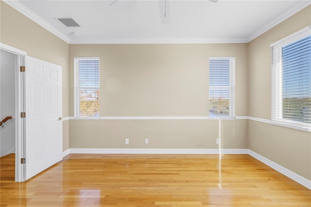 spare room featuring a ceiling fan, baseboards, visible vents, light wood finished floors, and crown molding