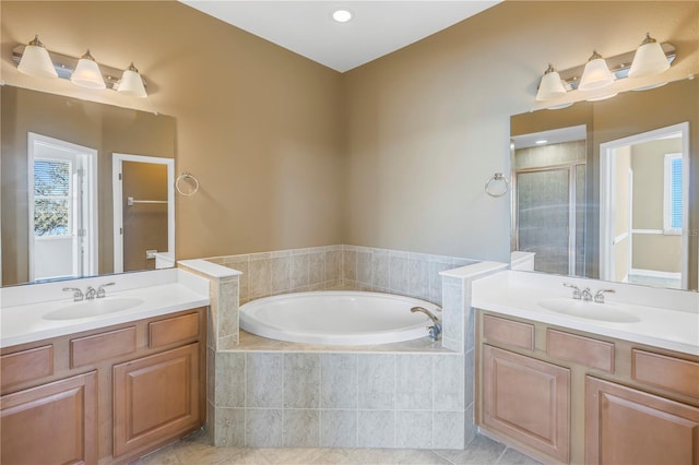 full bathroom with a garden tub, two vanities, a stall shower, and a sink