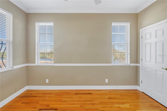 empty room featuring light wood finished floors, baseboards, and ornamental molding