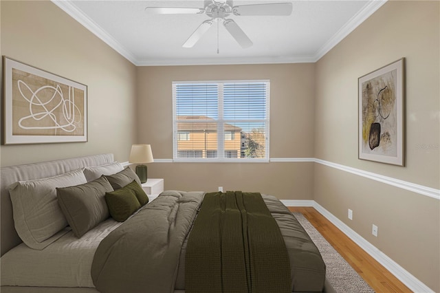 bedroom with ceiling fan, baseboards, wood finished floors, and crown molding