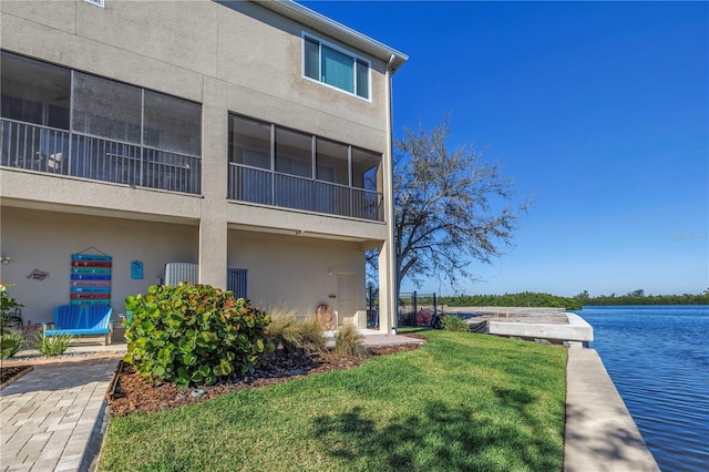 exterior space with a lawn, a water view, and stucco siding