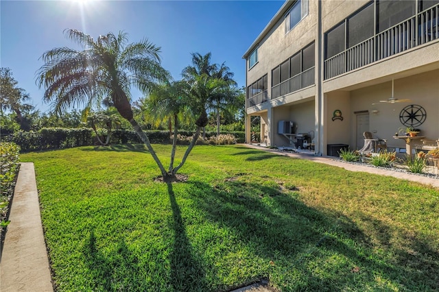 view of yard with a balcony, a ceiling fan, and a patio area