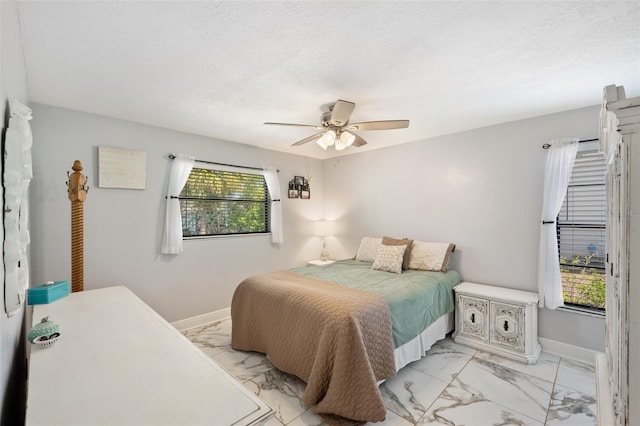 bedroom with marble finish floor, a textured ceiling, a ceiling fan, and baseboards