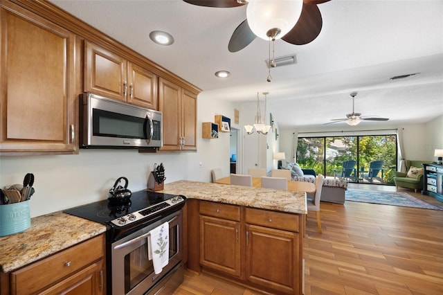 kitchen featuring open floor plan, ceiling fan with notable chandelier, a peninsula, and stainless steel appliances