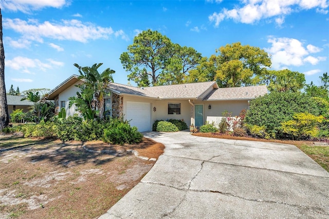 ranch-style home with a garage, driveway, and stucco siding