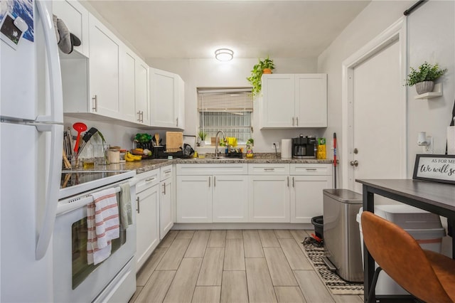 kitchen with white appliances, white cabinetry, wood finish floors, and a sink