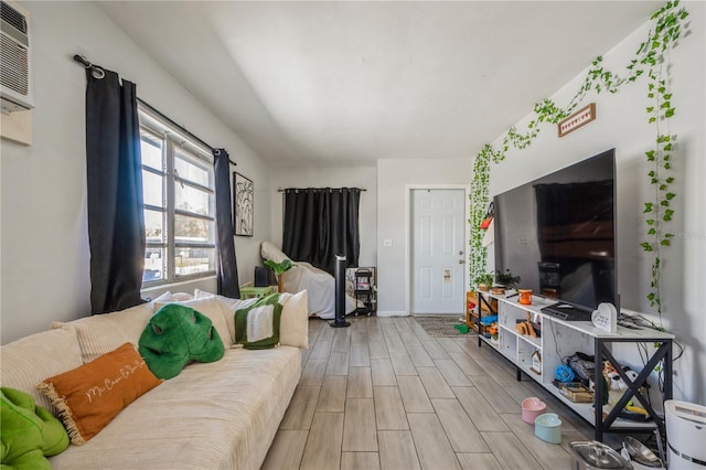 living area featuring wood finish floors, baseboards, and a wall mounted AC