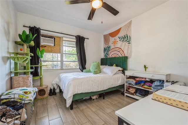 bedroom with ceiling fan, an AC wall unit, and wood finish floors