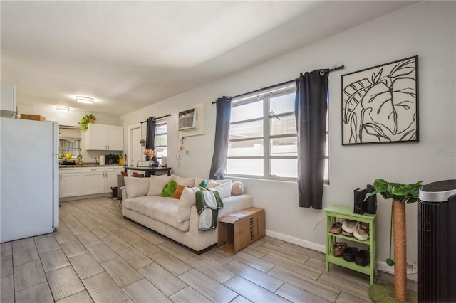 living area with a wall unit AC, baseboards, and wood finish floors