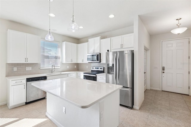 kitchen with a sink, stainless steel appliances, white cabinets, backsplash, and a center island