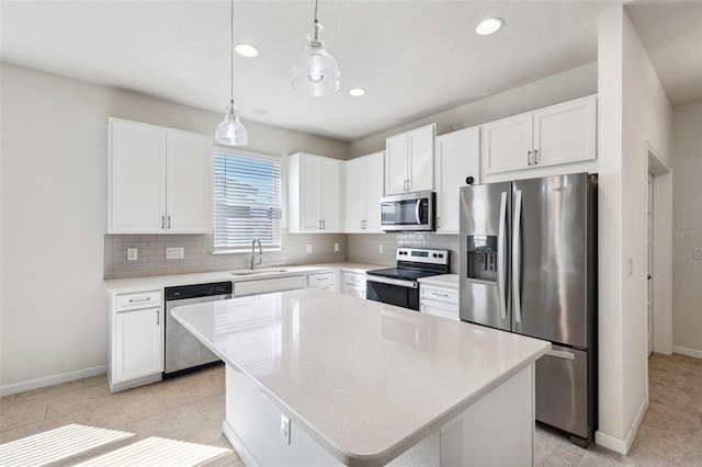 kitchen with a sink, decorative backsplash, stainless steel appliances, white cabinetry, and a center island