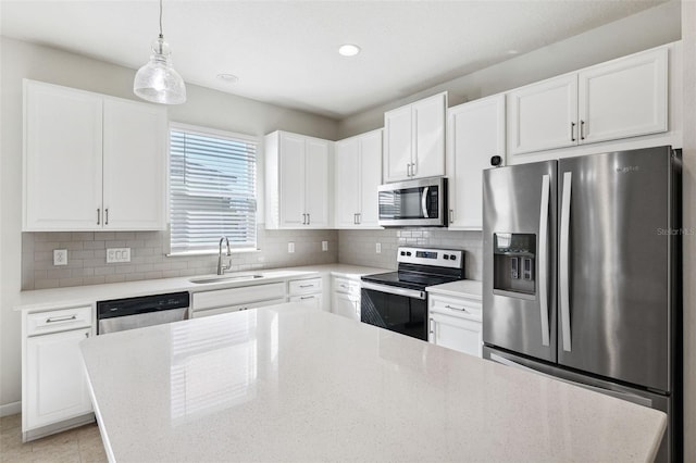 kitchen with tasteful backsplash, appliances with stainless steel finishes, white cabinetry, and a sink