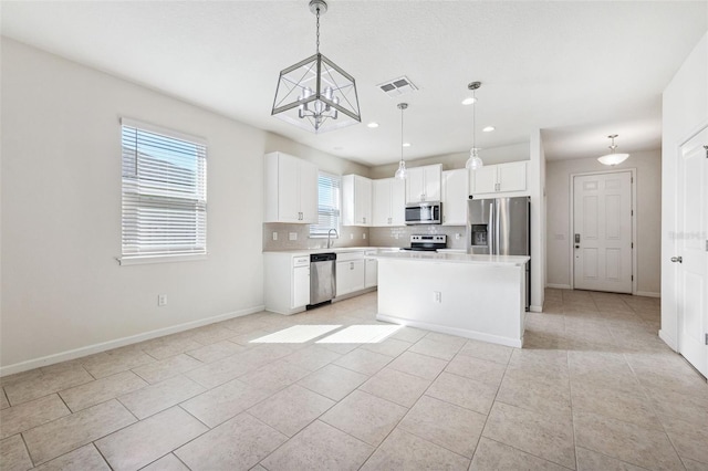 kitchen featuring tasteful backsplash, visible vents, a kitchen island, light countertops, and appliances with stainless steel finishes