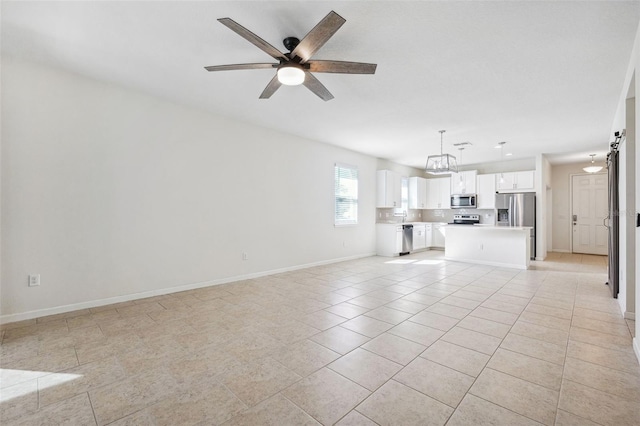 unfurnished living room with light tile patterned floors, ceiling fan with notable chandelier, and baseboards