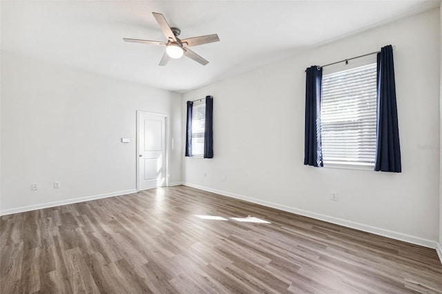 empty room featuring wood finished floors, a ceiling fan, and baseboards