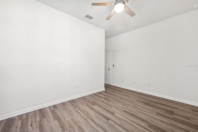 unfurnished room featuring baseboards, wood finished floors, visible vents, and ceiling fan