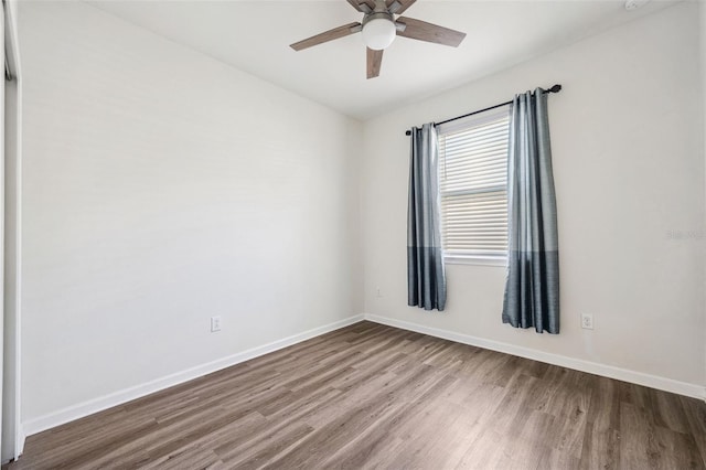 spare room featuring ceiling fan, baseboards, and wood finished floors