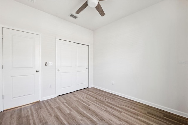 unfurnished bedroom with a ceiling fan, wood finished floors, visible vents, baseboards, and a closet