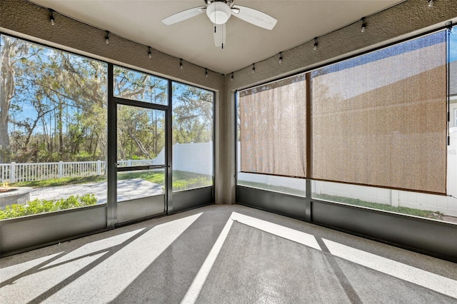 unfurnished sunroom with rail lighting and a ceiling fan