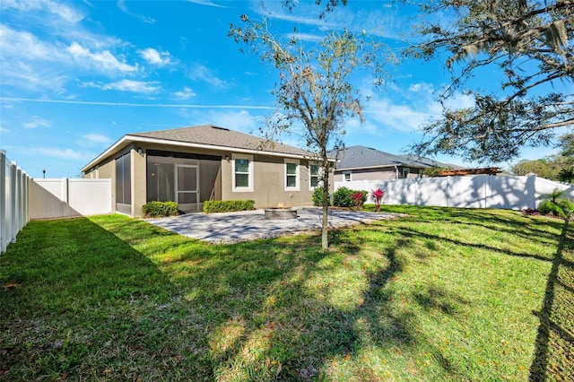 rear view of house with a lawn, a fenced backyard, a fire pit, a sunroom, and a patio area