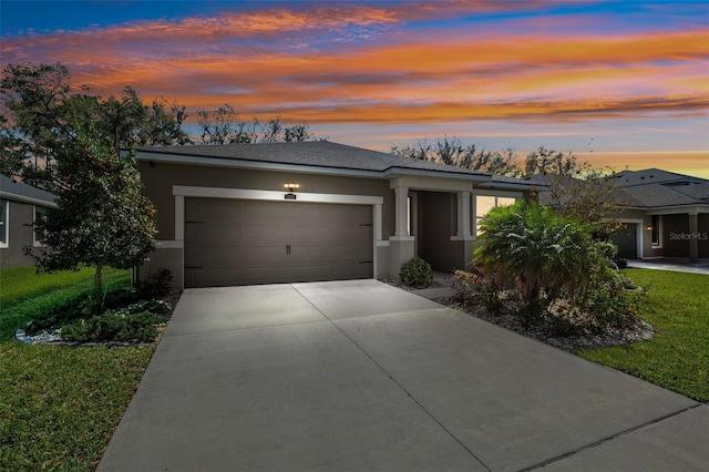 view of front of house with stucco siding, driveway, a shingled roof, and a garage