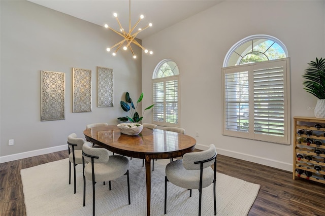 dining space with baseboards, dark wood-type flooring, a high ceiling, and a chandelier