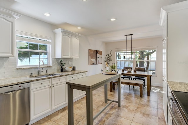 kitchen featuring light stone countertops, a sink, white cabinets, stainless steel dishwasher, and backsplash