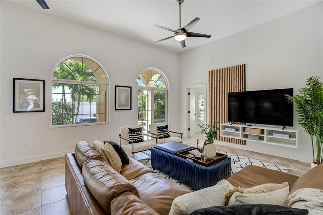 living area featuring tile patterned floors, a ceiling fan, and baseboards