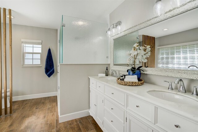 bathroom with a sink, baseboards, wood finished floors, and double vanity