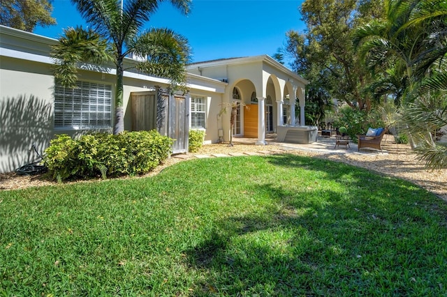 exterior space with stucco siding, a yard, and a patio area