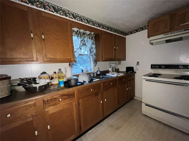 kitchen with light floors, white range with electric cooktop, a sink, under cabinet range hood, and dark countertops