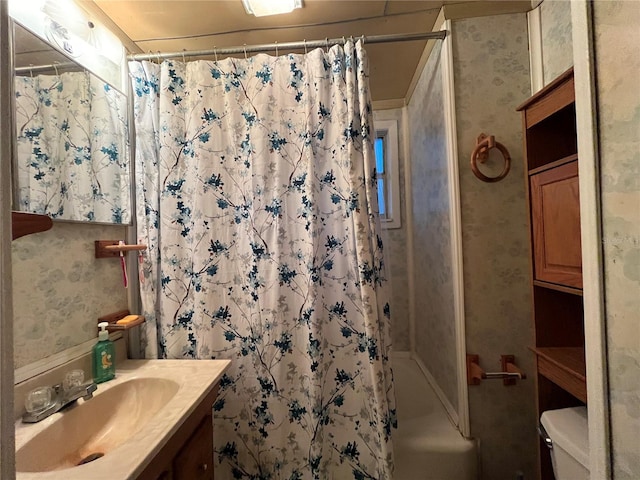 bathroom featuring shower / bath combo with shower curtain, toilet, wallpapered walls, and vanity