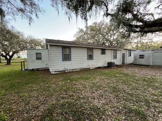 rear view of property featuring a yard and central air condition unit