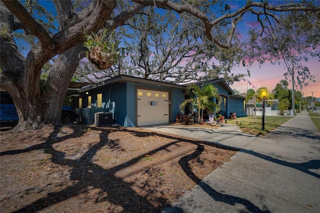 view of front of home featuring central air condition unit, stucco siding, an attached garage, and driveway